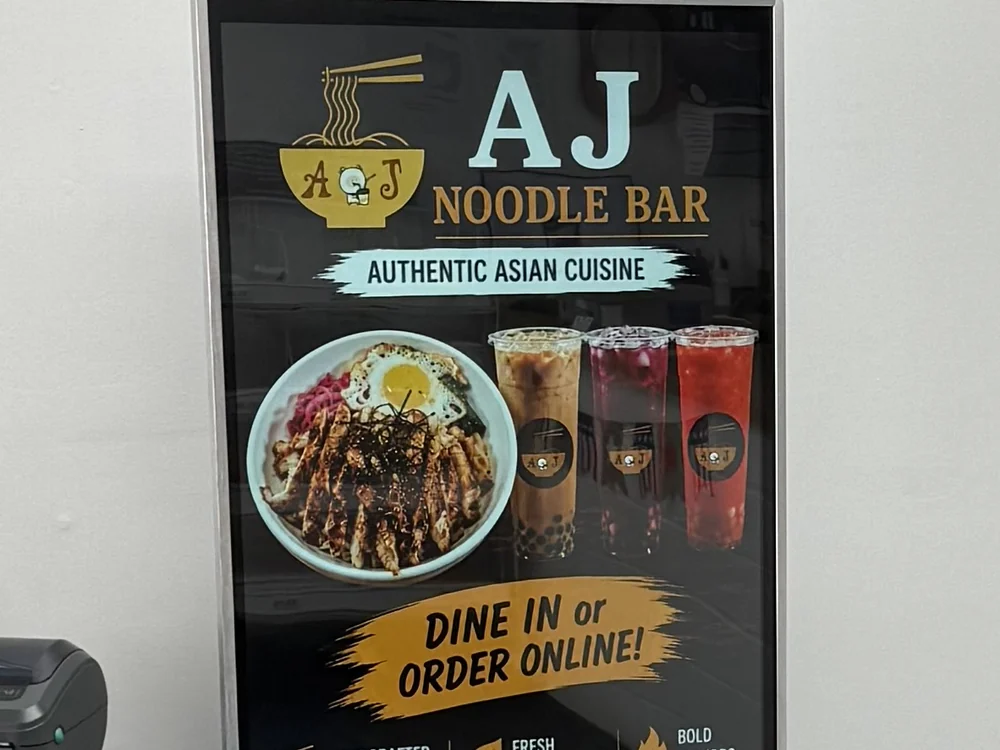 Freestanding floor totem in the network running an ad for AJ Noodle Bar