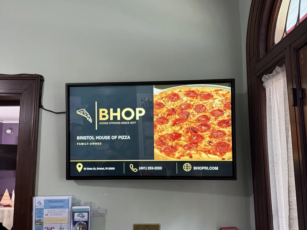 Wall-mounted screen in the network running an ad for Bristol House of Pizza