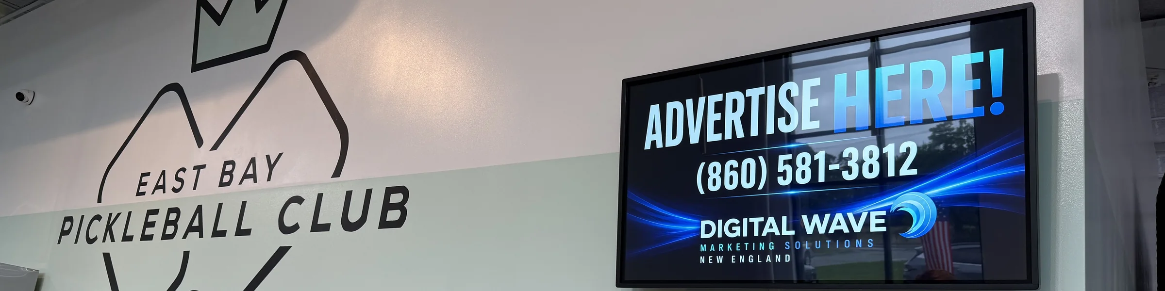 Wall-mounted Digital Wave screen at East Bay Pickleball Club in Warren, Rhode Island, beside the club&rsquo;s own logo