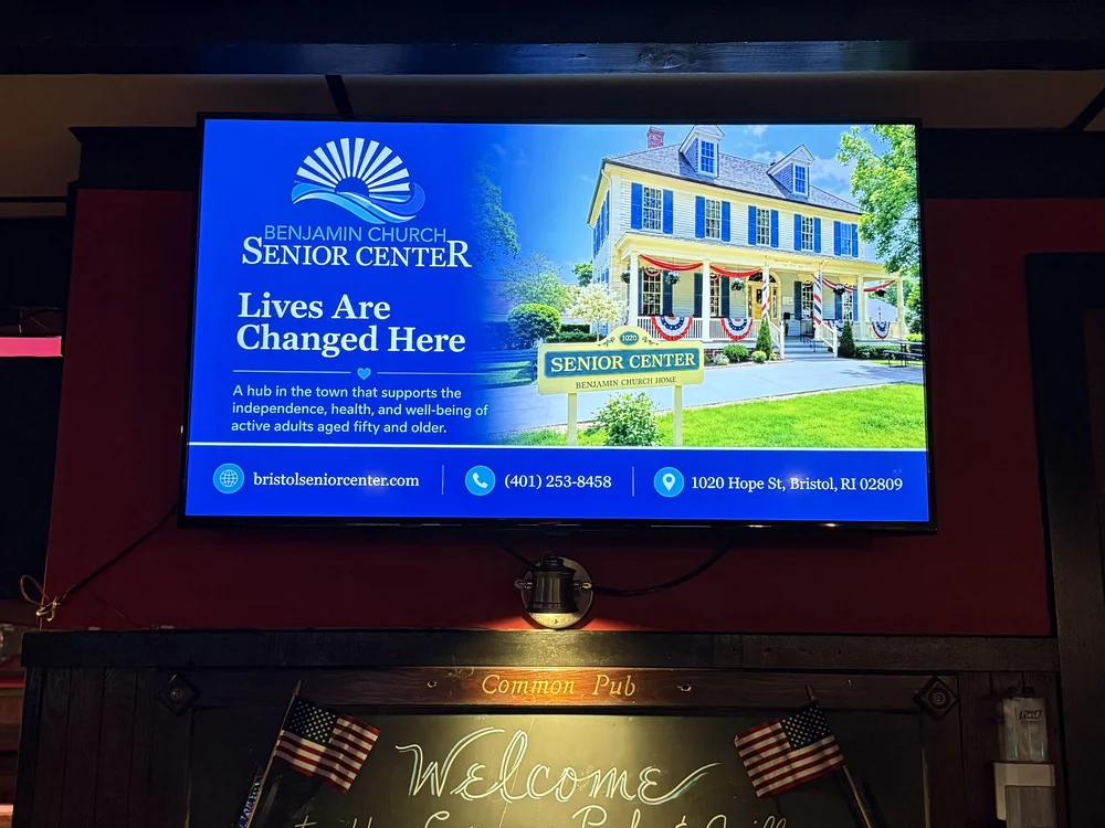 Wall screen at Common Pub & Grille in Bristol, Rhode Island running an ad for the Benjamin Church Senior Center