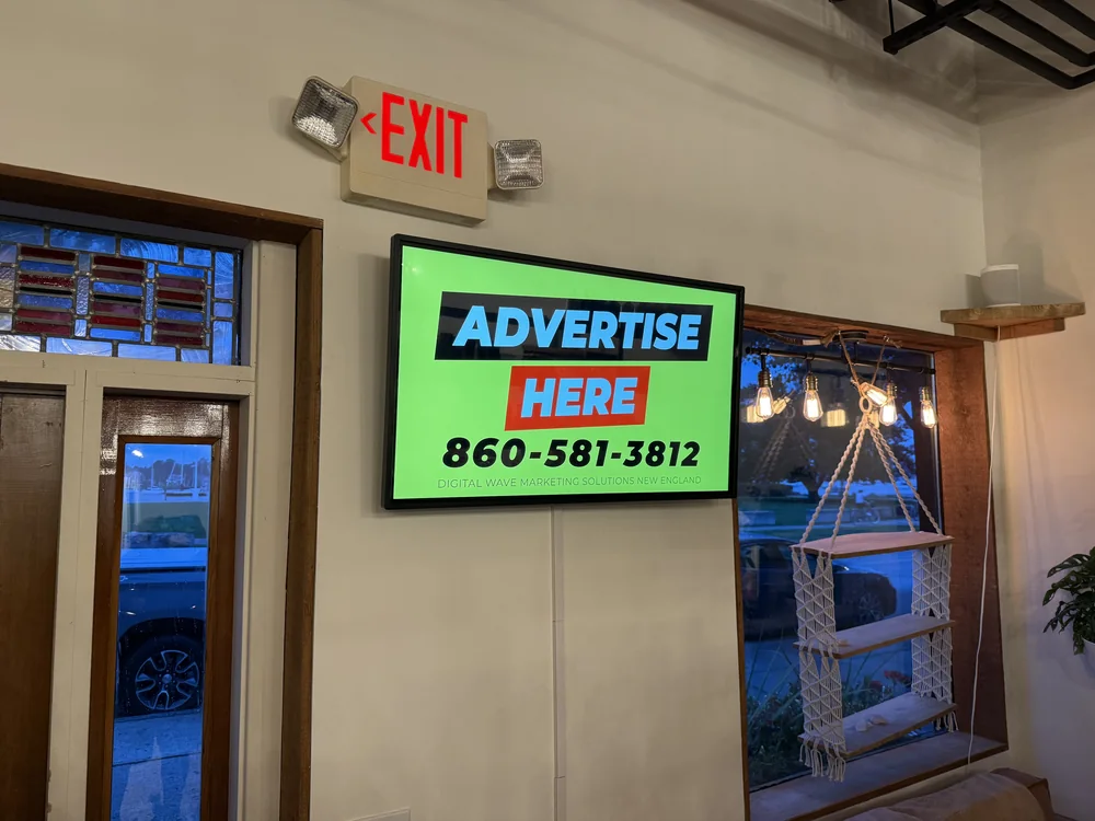 Wall-mounted screen at Pet Foods Plus in Bristol, Rhode Island, showing an Advertise Here card